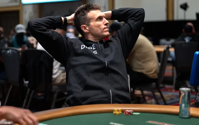Doug Polk at a poker table with hands behind his head during a WSOP tournament
