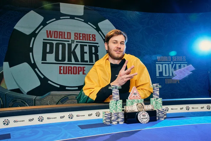 Marius Kudzmanas holds three fingers up for his third WSOP bracelet with chips and the gold bracelet on the table at WSOP Europe Prague