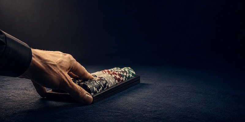 A rack of poker chips being pushed across the felt toward an empty seat, representing money sent out in a staking deal