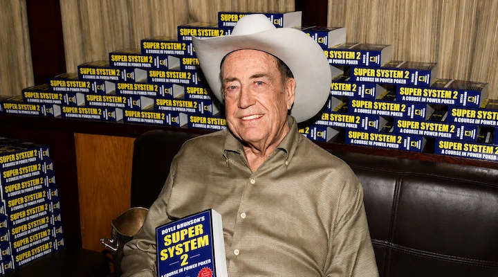 Doyle Brunson holding a copy of Super/System, the first poker strategy book written by a world champion