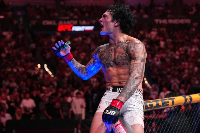 ACR Poker ambassador Tommy McMillen celebrates on top of the cage after a UFC Fight Night win