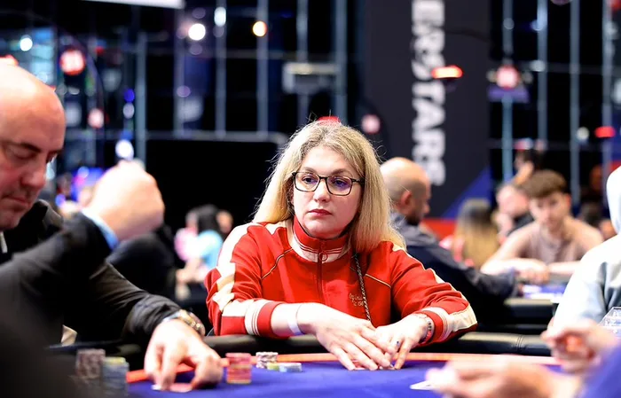 Almira Skripchenko, chess International Master and European Women's Champion, seated at a PokerStars tournament table in a red tracksuit
