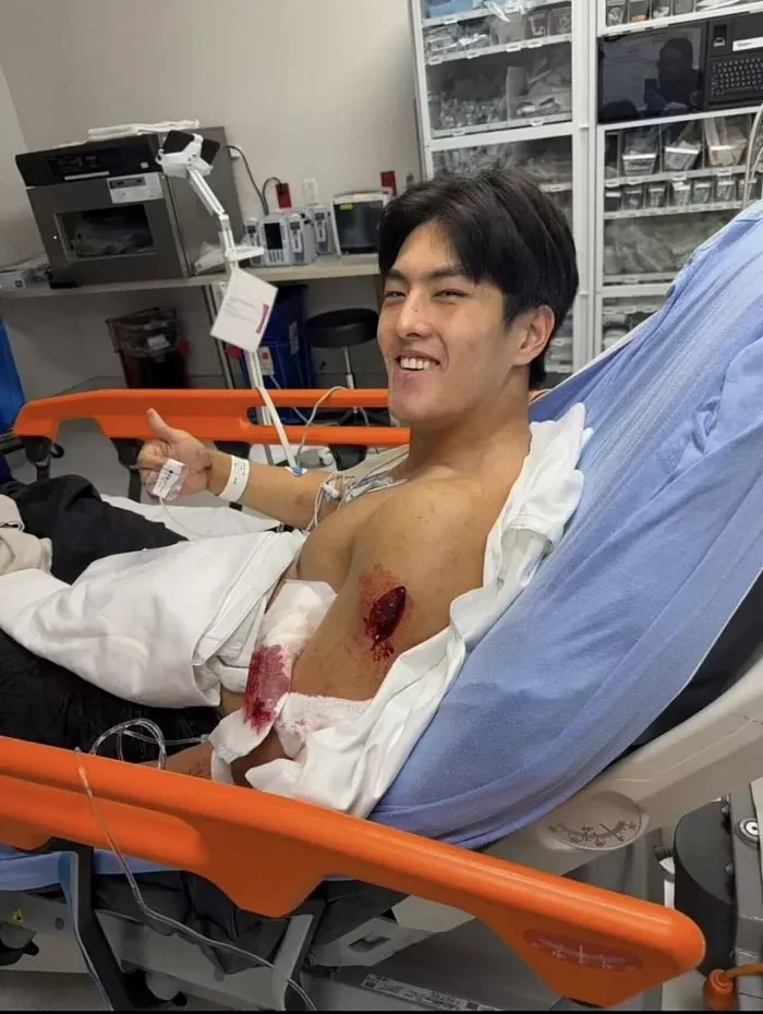Kevin Gao giving a thumbs-up from a hospital bed with a wound to his right shoulder, after the alleged Lynne Ji stabbing